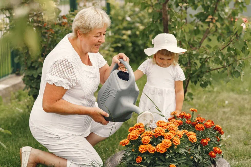 babcia i wnuczka podlewają kwiaty w ogrodzie
