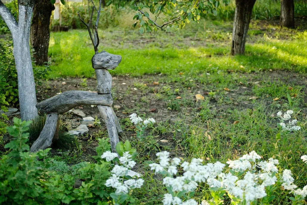 Drewniana figurka jelenia gdzieś na polanie.