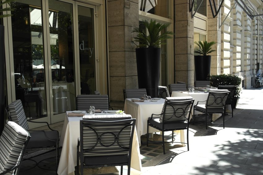 wysokie donice, stoliki i krzesła na chodniku przy restauracji